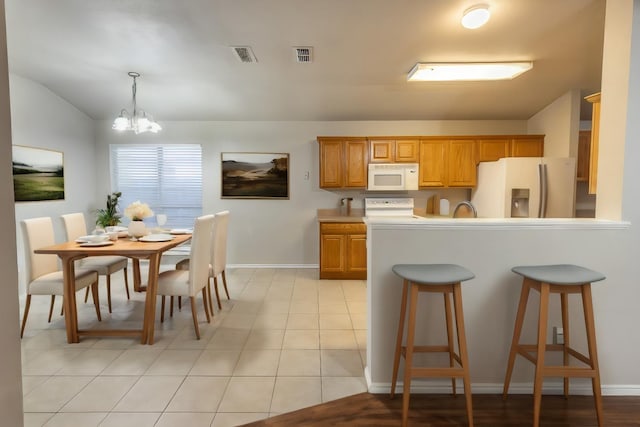 kitchen with pendant lighting, light tile patterned floors, range, an inviting chandelier, and fridge with ice dispenser