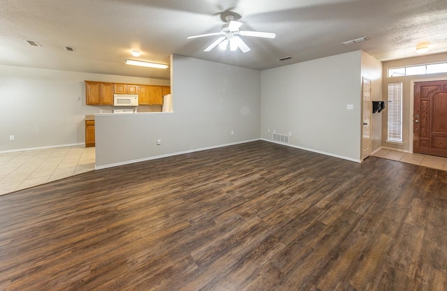 unfurnished living room with ceiling fan, wood-type flooring, and a textured ceiling