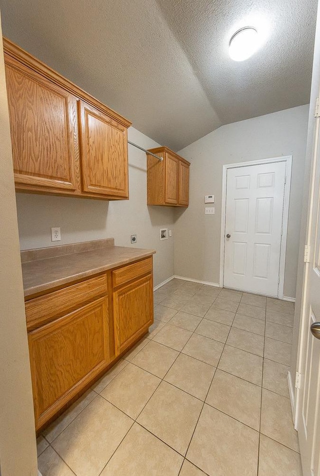 laundry room with cabinets, hookup for a washing machine, a textured ceiling, and light tile patterned floors