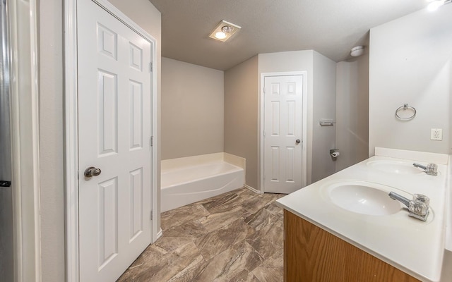 bathroom with vanity, a textured ceiling, and a bathtub