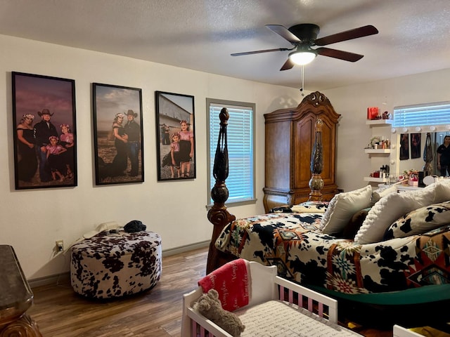 bedroom with ceiling fan, wood-type flooring, and a textured ceiling