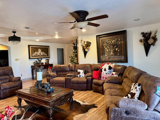 living room with ceiling fan, light hardwood / wood-style floors, and a textured ceiling