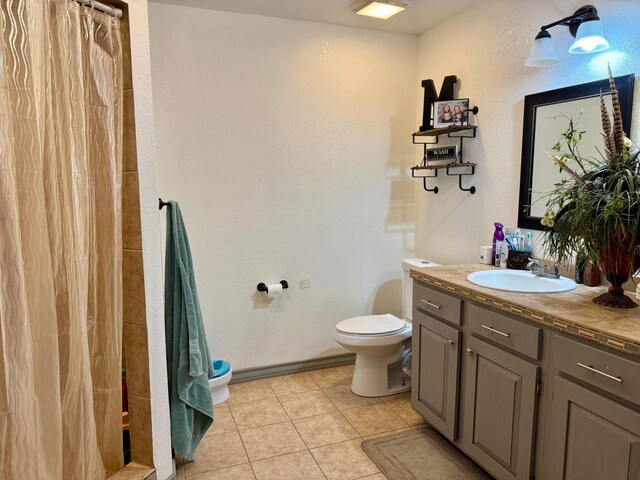 bathroom with tile patterned flooring, vanity, walk in shower, and toilet