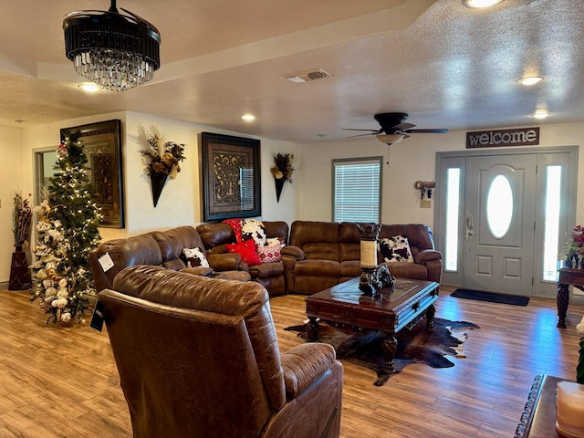 living room featuring a notable chandelier, light hardwood / wood-style flooring, and a textured ceiling