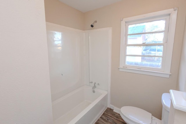 bathroom with wood-type flooring, shower / bathing tub combination, and toilet