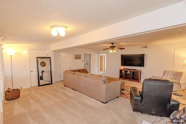 living room featuring ceiling fan, light colored carpet, and a textured ceiling