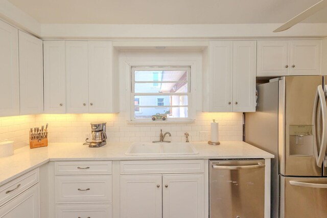 kitchen featuring sink, backsplash, white cabinets, and appliances with stainless steel finishes