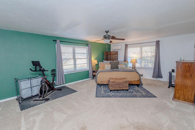 carpeted bedroom featuring multiple windows, a textured ceiling, a wall unit AC, and ceiling fan