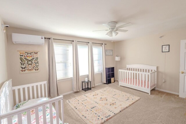 bedroom featuring ceiling fan, a crib, light colored carpet, and a wall mounted AC