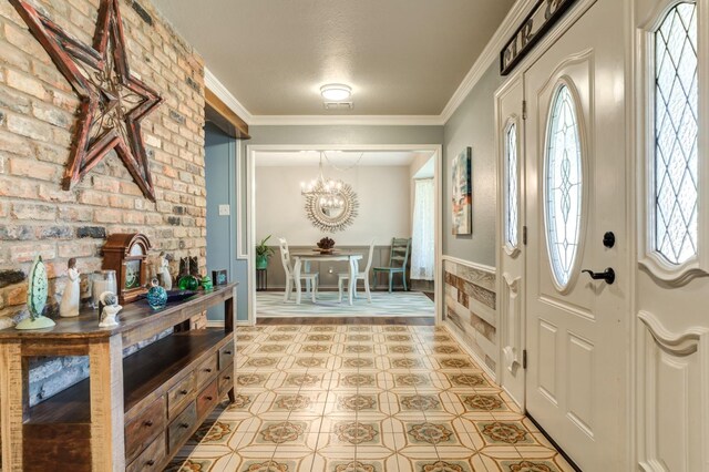 entryway with ornamental molding and a chandelier