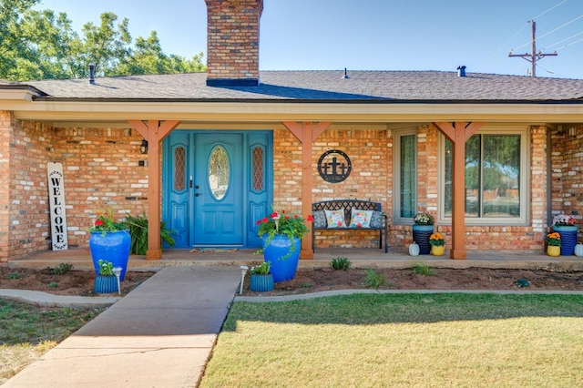 property entrance with covered porch and a lawn