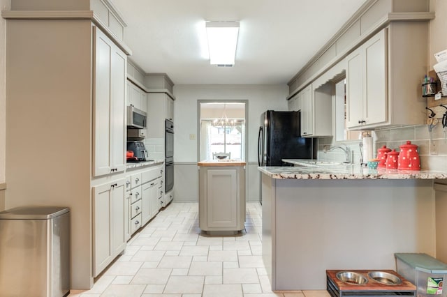 kitchen with a chandelier, kitchen peninsula, stainless steel appliances, light stone countertops, and decorative backsplash