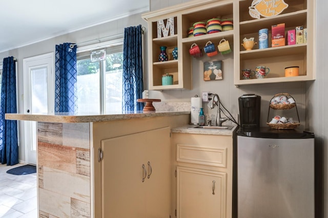 interior space with stainless steel refrigerator, cream cabinets, and sink