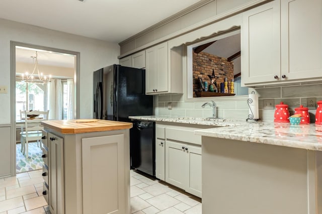 kitchen featuring a kitchen island, backsplash, black appliances, light stone countertops, and an inviting chandelier