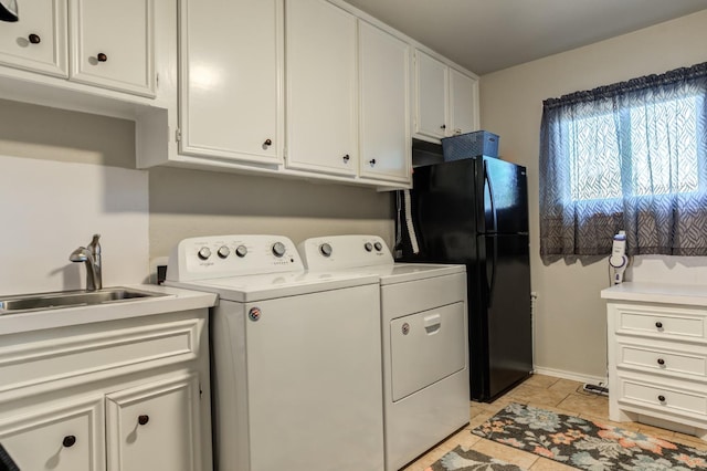 clothes washing area with sink, washer and clothes dryer, and cabinets