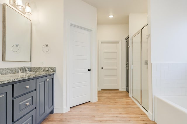 bathroom with plus walk in shower, hardwood / wood-style floors, and vanity