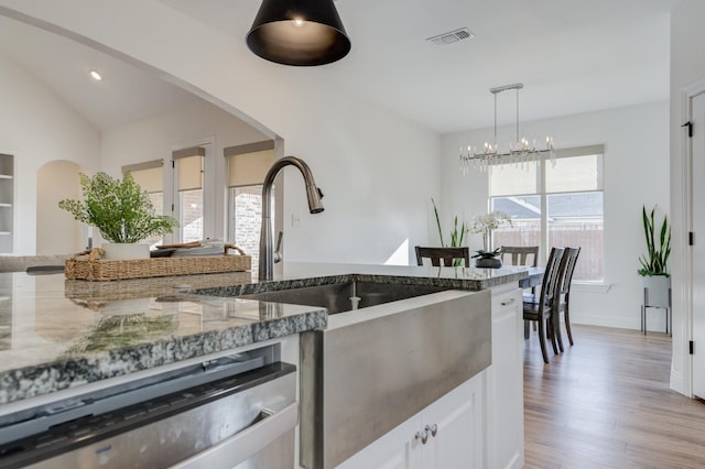 kitchen with dishwasher, sink, dark stone countertops, white cabinets, and light hardwood / wood-style flooring