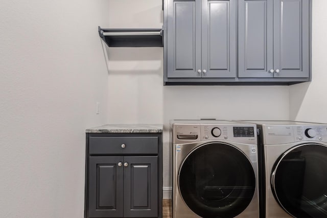 washroom with hardwood / wood-style floors, cabinets, and washing machine and clothes dryer