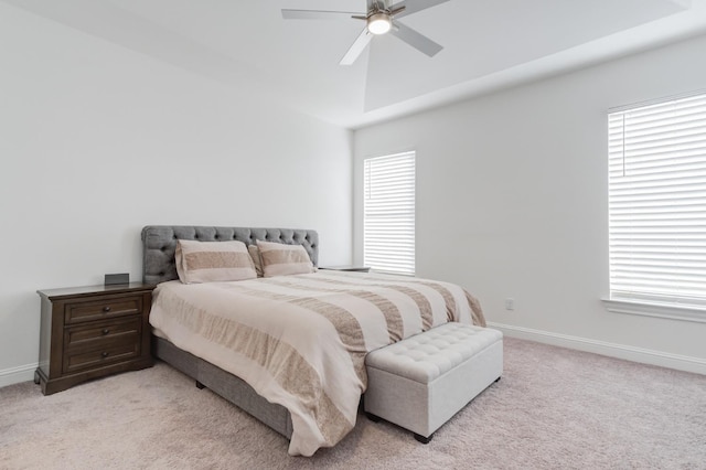 carpeted bedroom featuring multiple windows, a raised ceiling, and ceiling fan