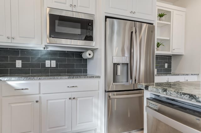 kitchen featuring white cabinetry, stainless steel appliances, light stone counters, and backsplash