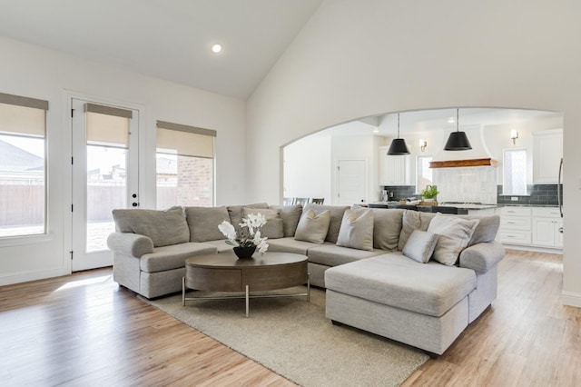 living room with high vaulted ceiling and light wood-type flooring