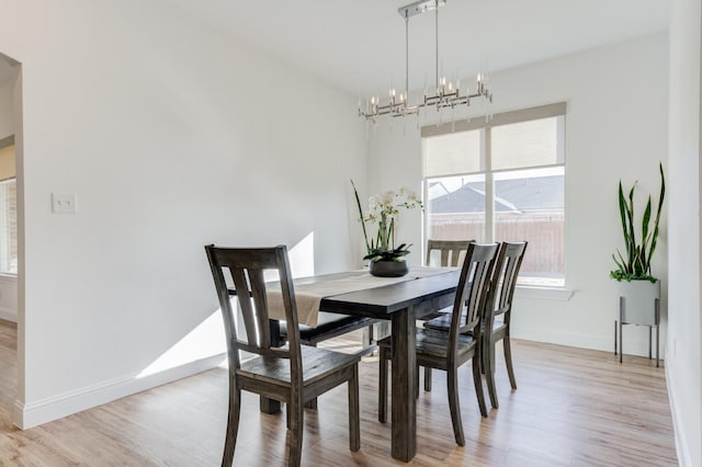 dining space with light hardwood / wood-style floors and a chandelier