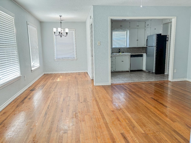 interior space with a notable chandelier, light hardwood / wood-style floors, sink, and a textured ceiling