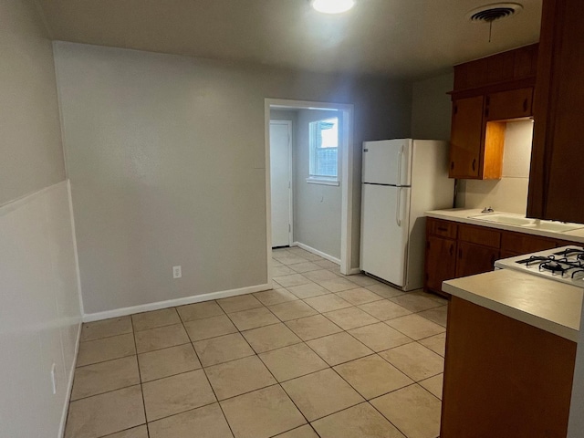 kitchen with light tile patterned flooring, white fridge, and range