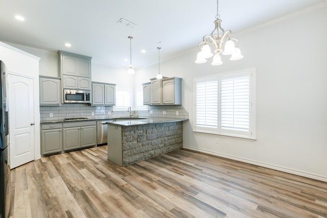 208 Berkshire Ave, Wolfforth, TX 79382 - kitchen featuring a peninsula, gray cabinets, tasteful backsplash, a sink, and stainless steel appliances