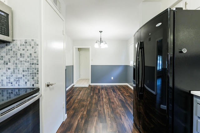 5418 15th St, Lubbock, TX 79416 - kitchen featuring freestanding refrigerator, stainless steel microwave, a chandelier, backsplash, and dark wood-style flooring