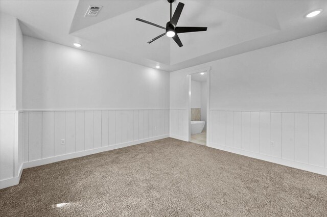 unfurnished room featuring a raised ceiling, ceiling fan, and carpet flooring