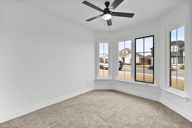 spare room featuring ceiling fan, carpet, and a wealth of natural light