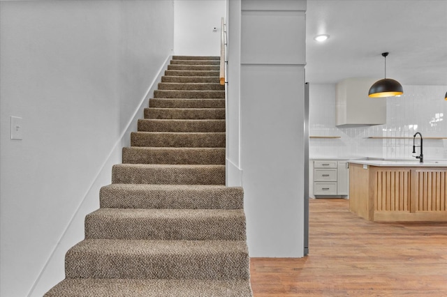 staircase with hardwood / wood-style flooring and sink