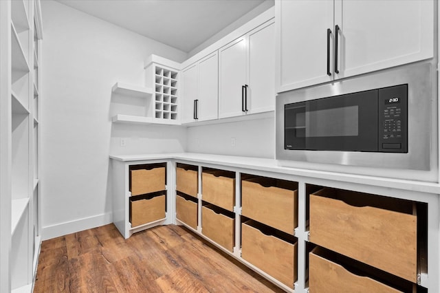 kitchen featuring built in microwave, white cabinetry, and light hardwood / wood-style flooring