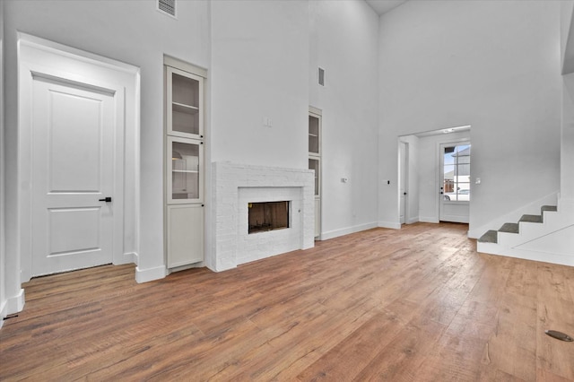 unfurnished living room with a high ceiling, hardwood / wood-style floors, and a fireplace