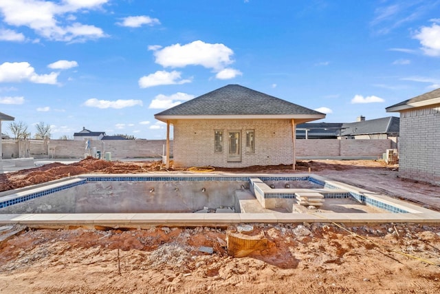 rear view of property with a pool with hot tub