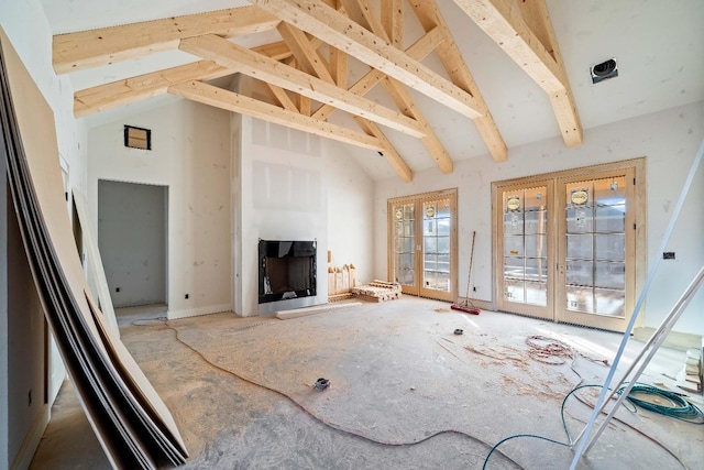 unfurnished living room featuring french doors and high vaulted ceiling