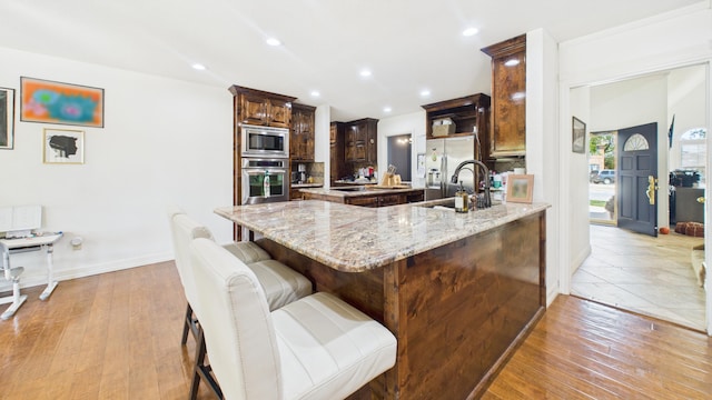 4615 94th St, Lubbock, TX 79424 - kitchen featuring stainless steel appliances, a sink, a breakfast bar, a peninsula, and light stone countertops