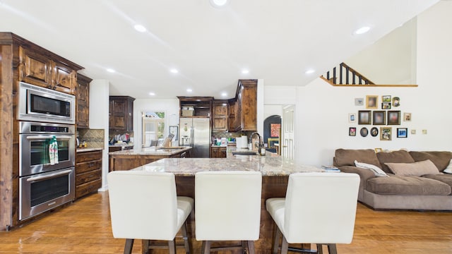 4615 94th St, Lubbock, TX 79424 - kitchen with stainless steel appliances, a sink, a kitchen island, backsplash, and a kitchen bar