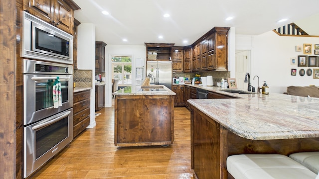 4615 94th St, Lubbock, TX 79424 - kitchen with a sink, appliances with stainless steel finishes, light wood-type flooring, a peninsula, and a center island