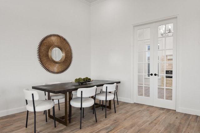 dining space featuring wood-type flooring, ornamental molding, and french doors