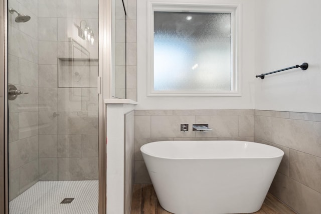 bathroom with shower with separate bathtub and tile walls