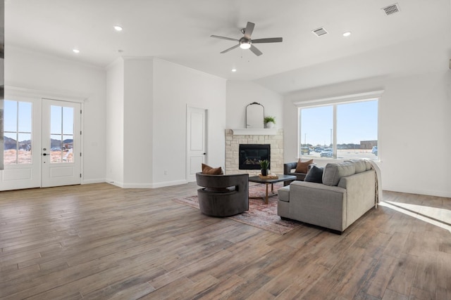 living room with plenty of natural light, hardwood / wood-style floors, and a stone fireplace