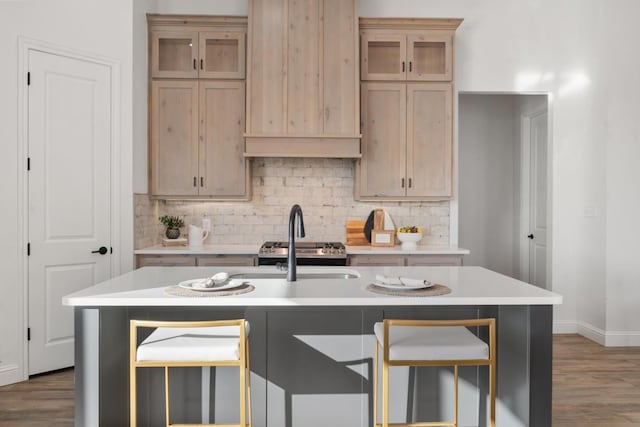 kitchen with a kitchen island with sink, decorative backsplash, and light brown cabinets