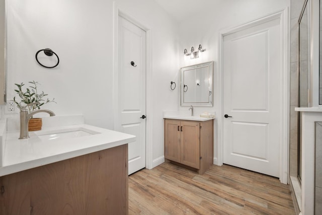 bathroom featuring hardwood / wood-style flooring, vanity, and an enclosed shower