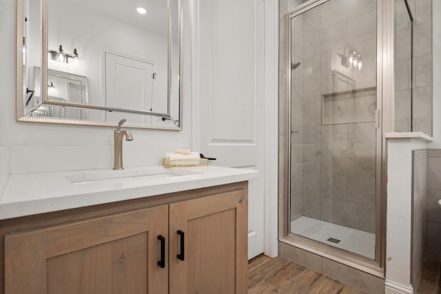 bathroom with walk in shower, vanity, and hardwood / wood-style floors