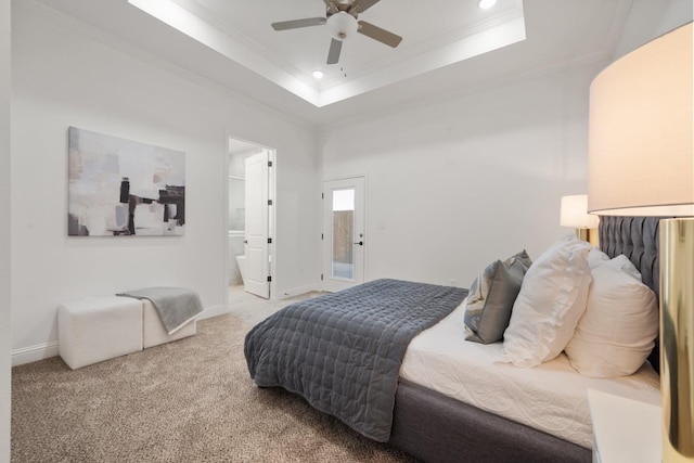 carpeted bedroom featuring ornamental molding, ceiling fan, ensuite bath, and a tray ceiling