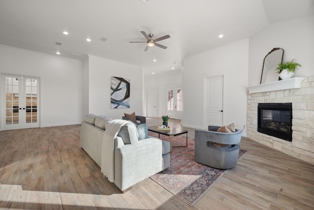 living room with crown molding, a fireplace, french doors, and light wood-type flooring