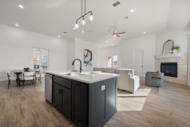 kitchen with decorative light fixtures, an island with sink, sink, stainless steel dishwasher, and french doors