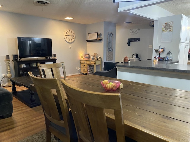 dining room with wood-type flooring and a textured ceiling